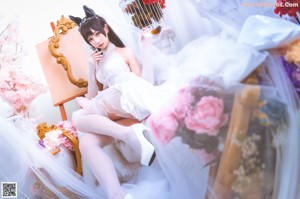 A woman in a wedding dress sitting on a bed.