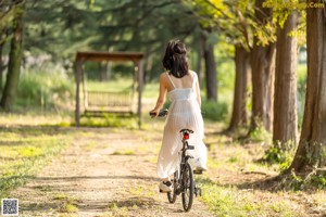 A woman in a white dress standing in a park.