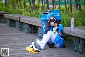 A woman sitting in a trash can holding a baseball bat.