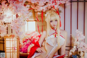 A woman in a white and red lingerie sitting on a bed.