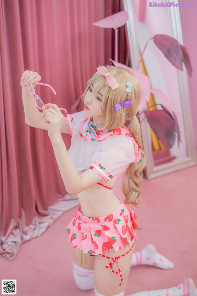 A woman in a pink and white outfit holding a pair of glasses.