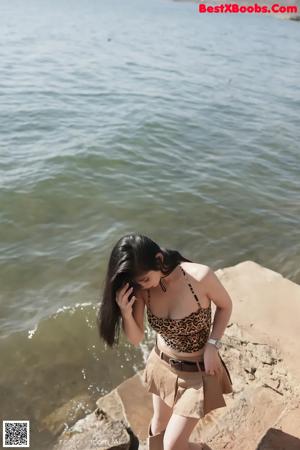 A woman in a leopard print bikini sitting on a red couch.