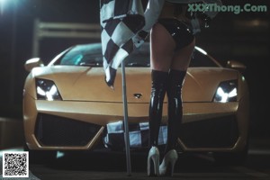 A woman holding a checkered flag in front of a car.