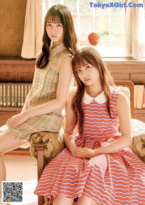 A couple of young women standing next to each other on a sidewalk.