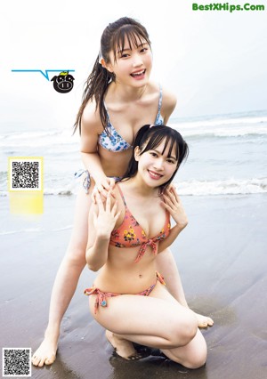 Two women in bikinis standing next to a swimming pool.