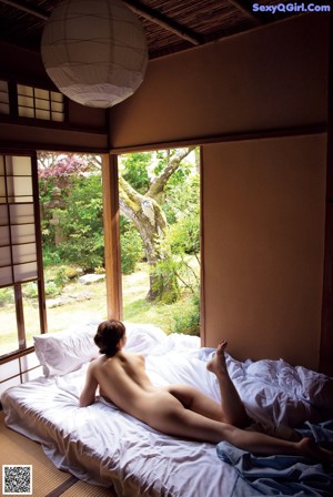 A naked asian woman sitting on a tatami mat.
