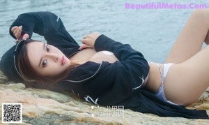 A woman in a black hoodie sitting on a rock.