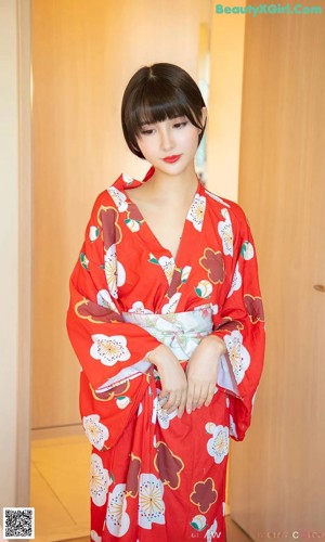 A woman in a red kimono sitting on a table.