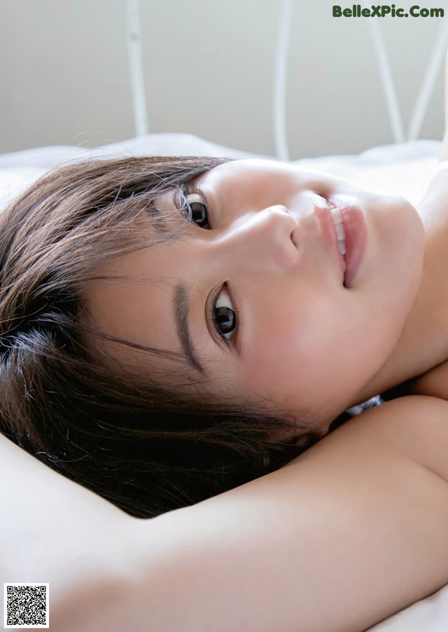 A woman laying on top of a white bed.