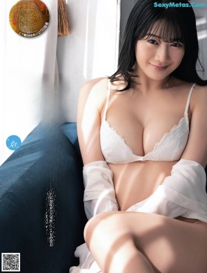 A woman in a blue bra sitting on a white floor.