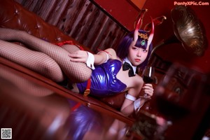 A woman dressed as a devil sitting at a bar.
