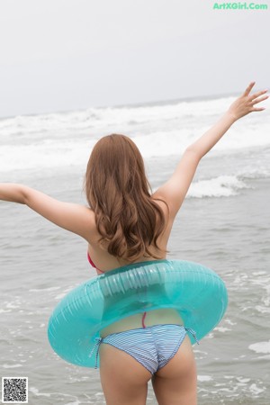 A woman in a blue and white striped bikini standing next to a pool.